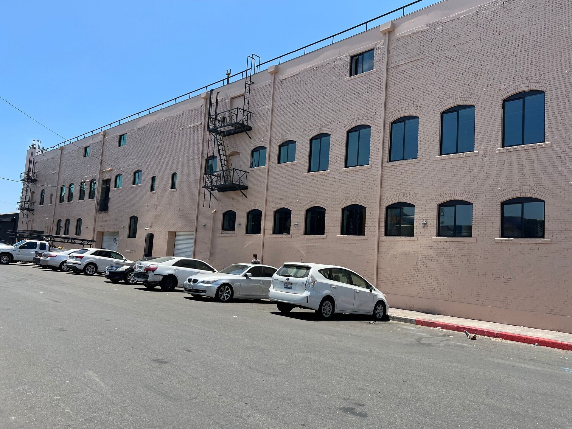 A row of cars are parked in front of a large building.
