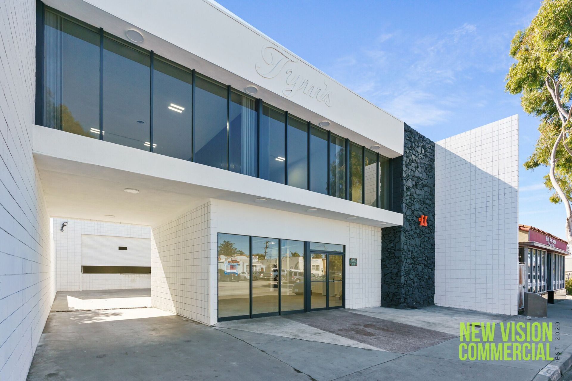 A large white building with a lot of windows is for sale by new vision commercial