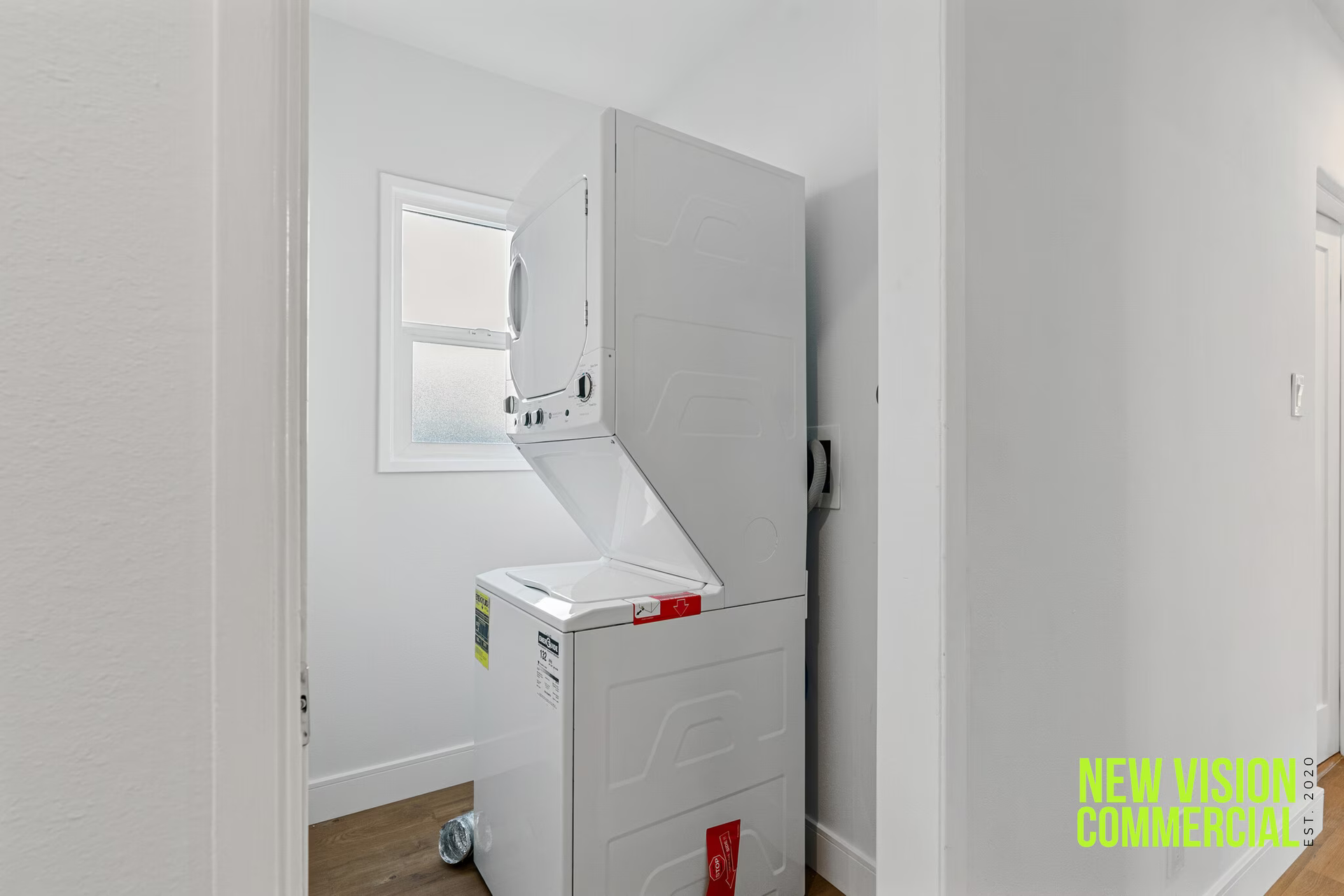 A washer and dryer are in a laundry room next to a window.