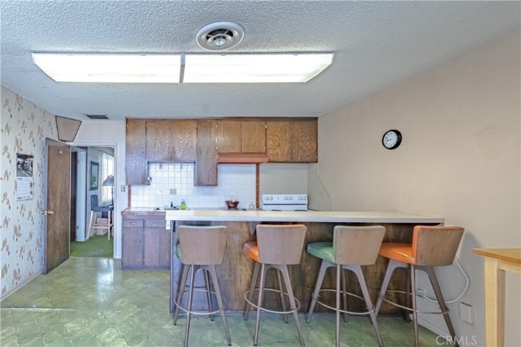 A kitchen with a bar and stools and a clock on the wall