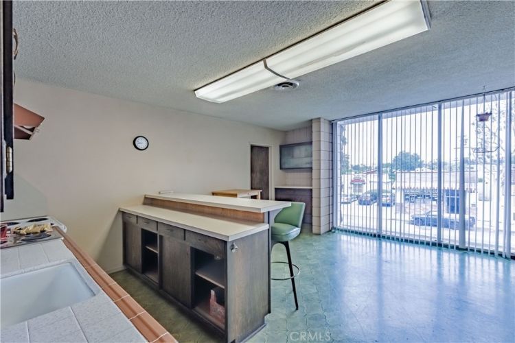 A kitchen with a sink and stools and a large window