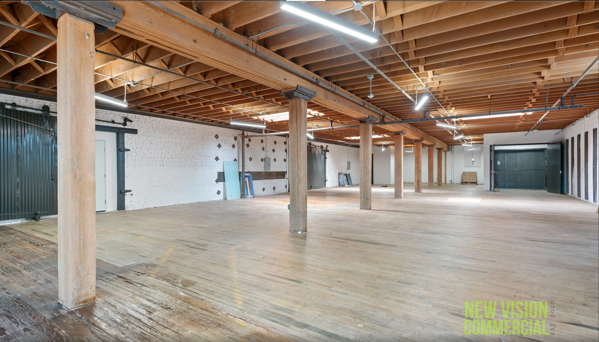 A large empty room with wooden beams and columns.