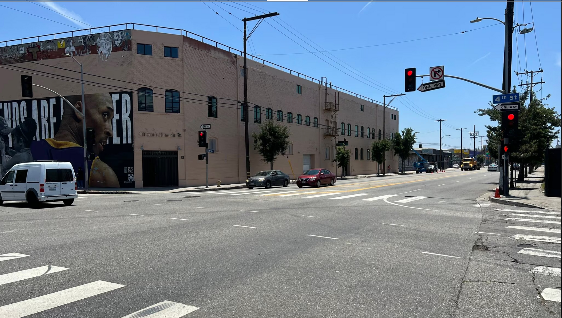 A white van is driving down a street in front of a building that says 