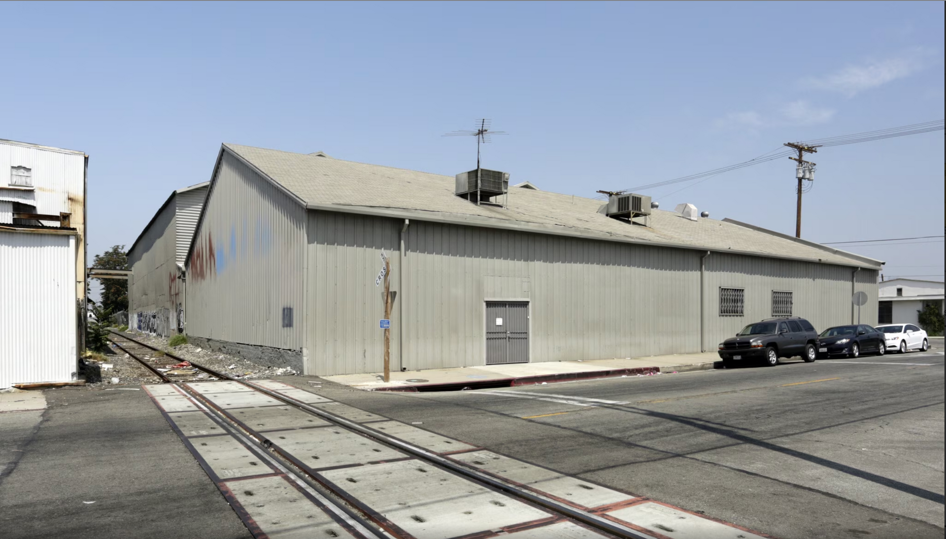A building next to train tracks with cars parked in front of it