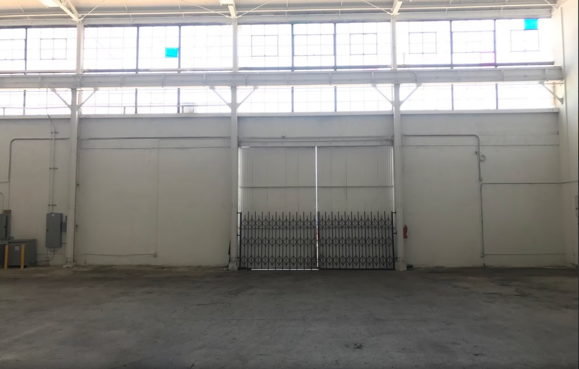 An empty warehouse with a gate and a lot of windows.