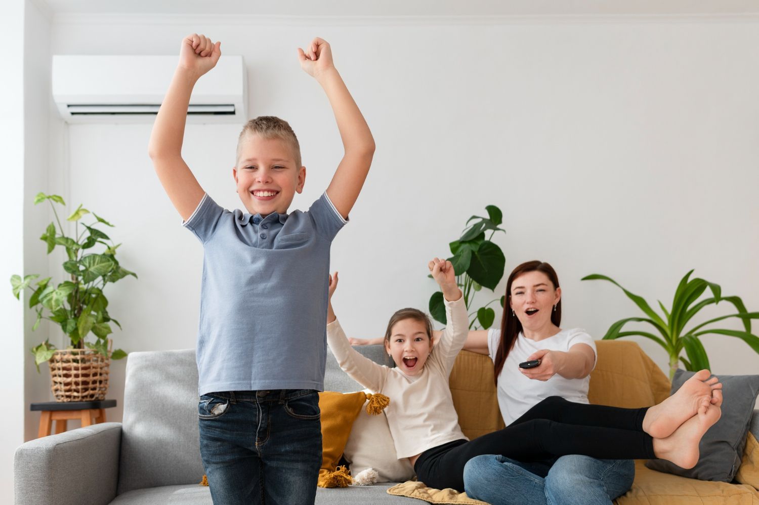 Family celebrating on a couch, cheering with raised arms in a bright living room