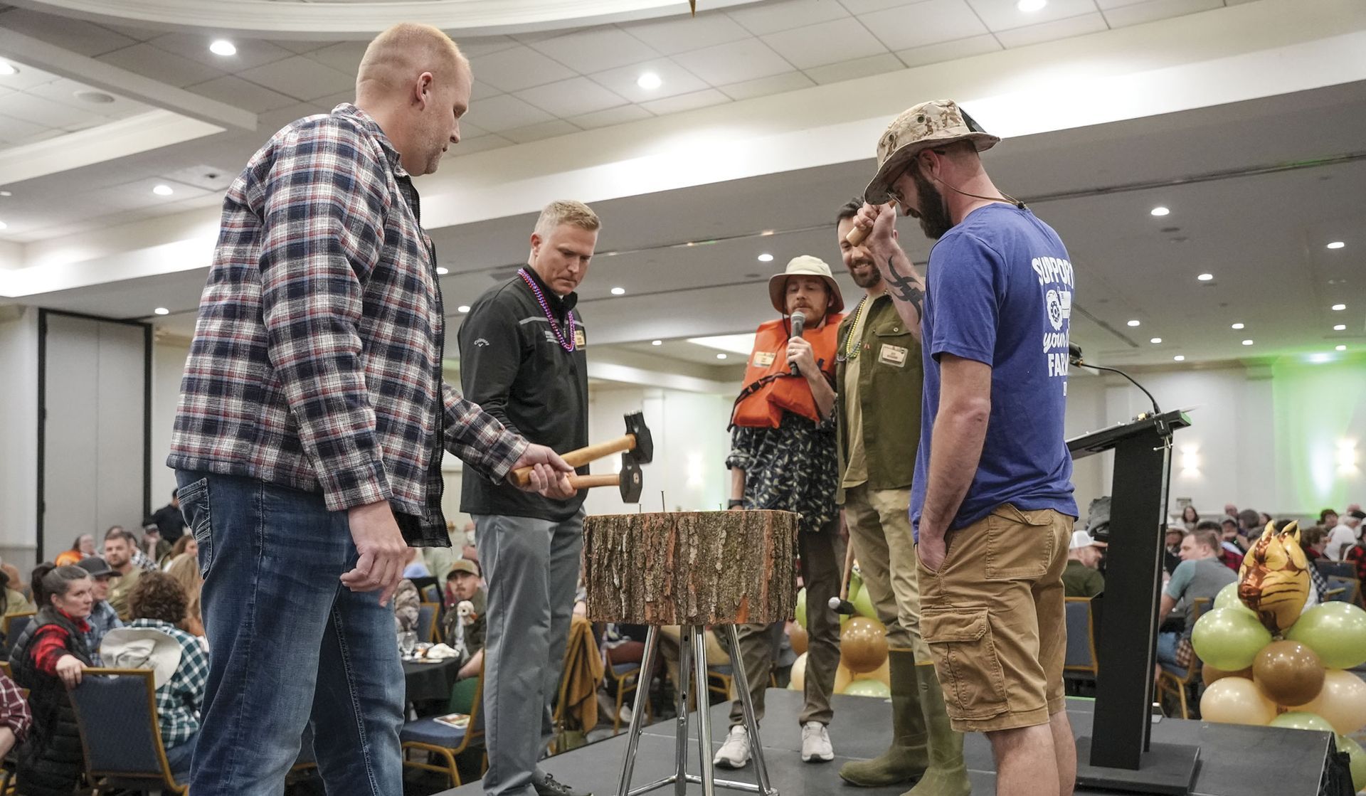 Four men with hammers pounding nails into a stump (game for the event)