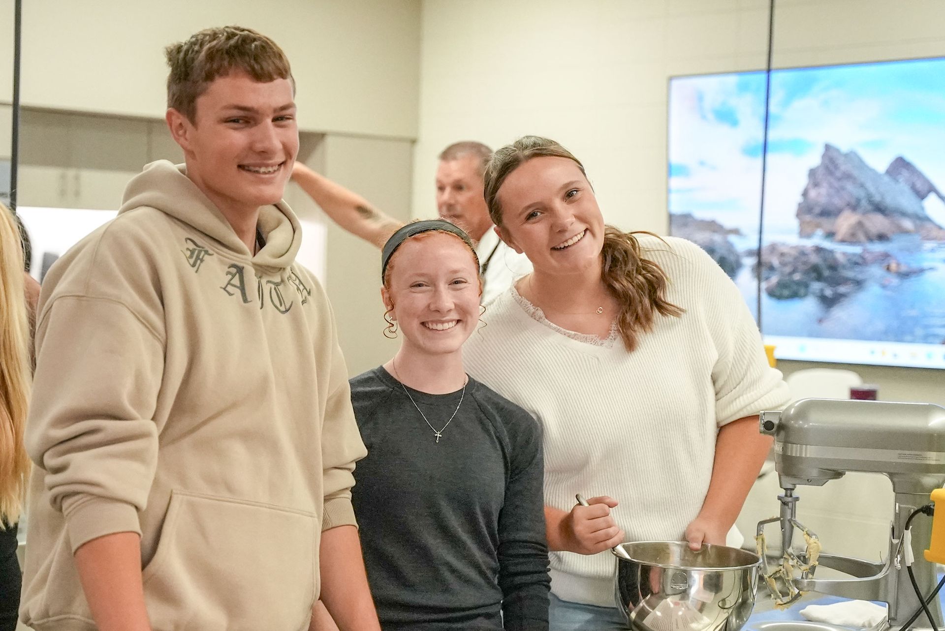 Two smiling female and one smiling male students at their culinary arts station.