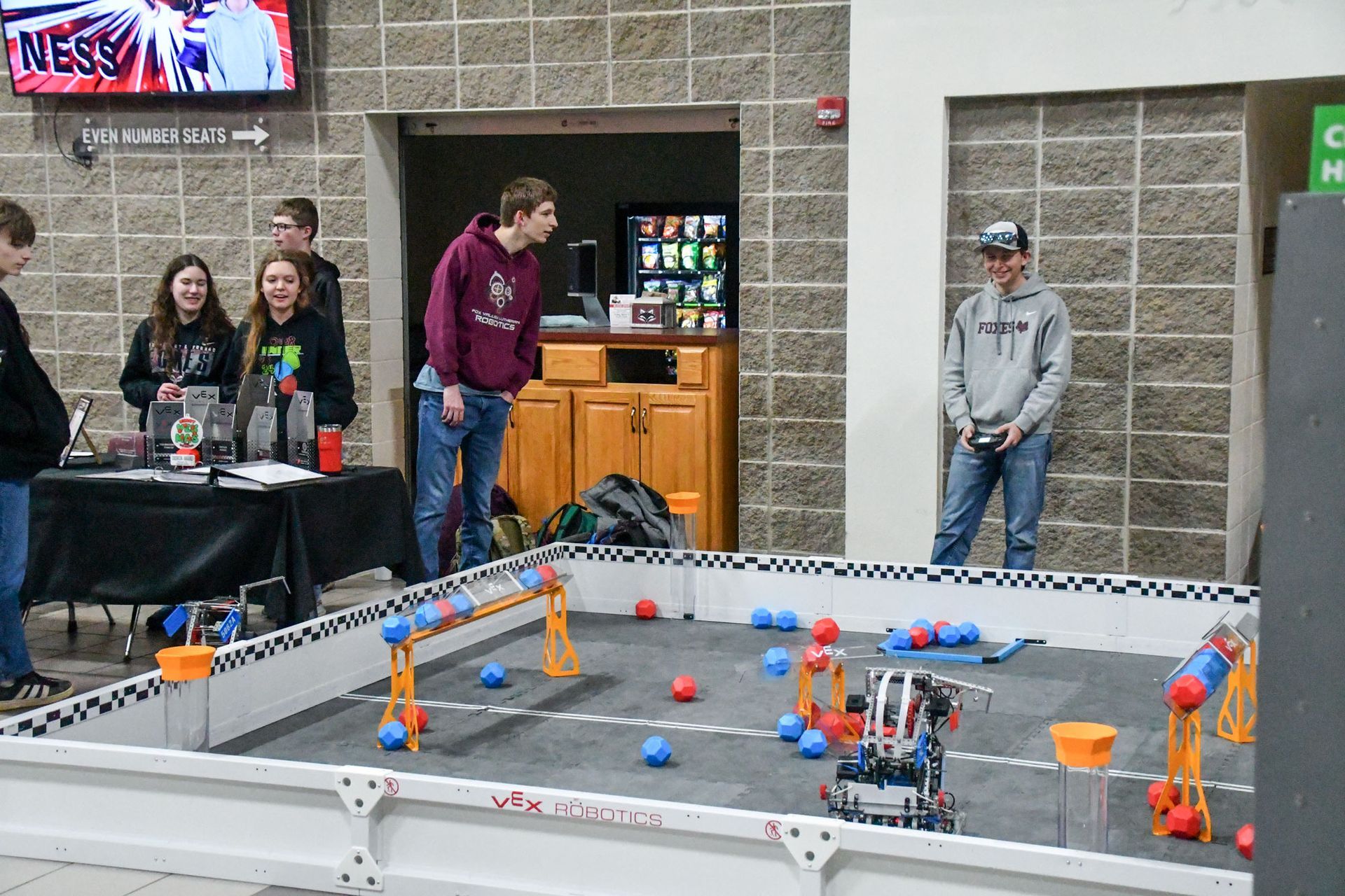 Two male students by the robotics table, moving robots through the course