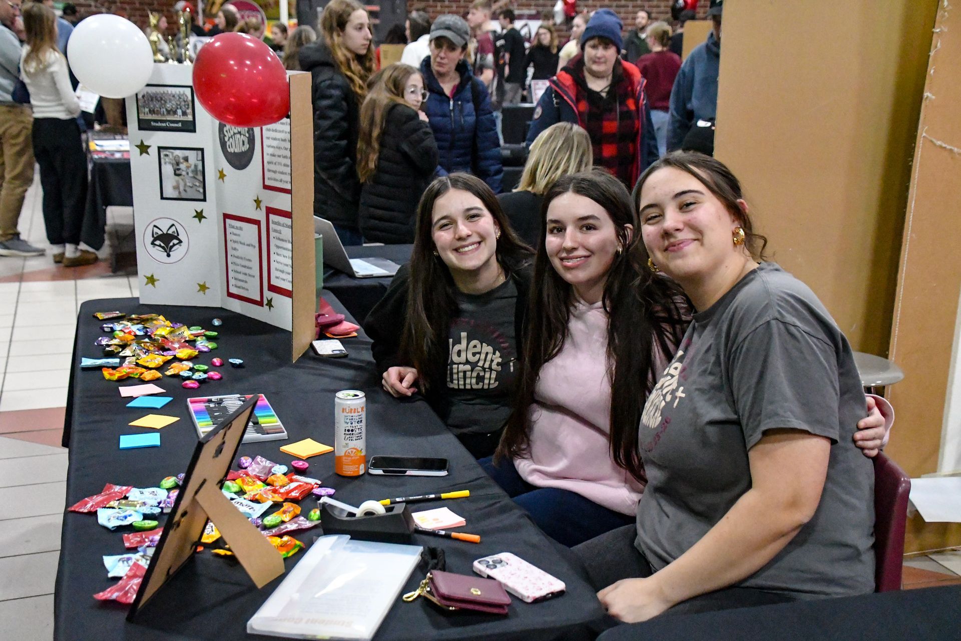 Three smiling girls, looking at camera, while sitting at their table
