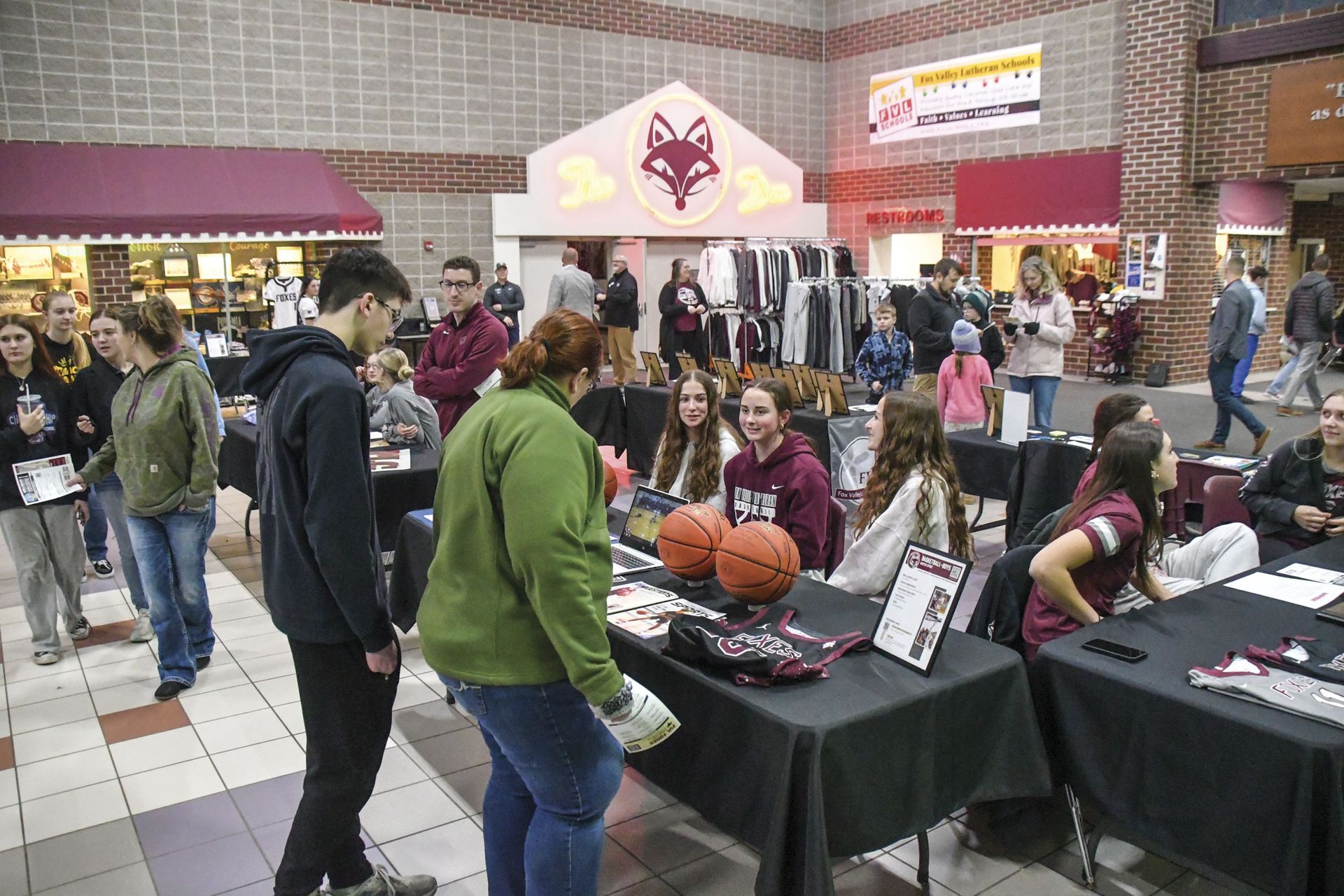 Visitors and booths in Commons for the Open House event - momm and son at basketball table