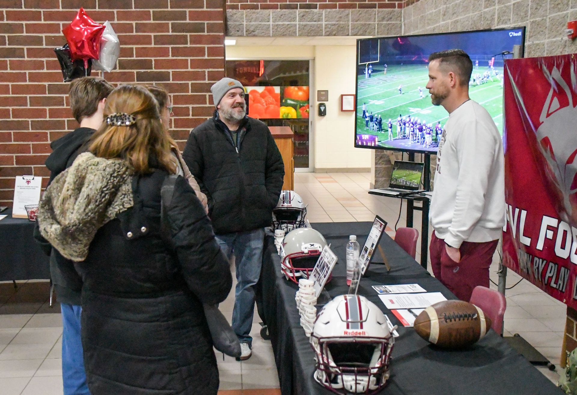 Football coach talking to family, by the football display