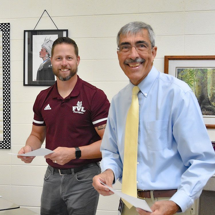 Two smiling, welcoming, male teachers, in the Media Center