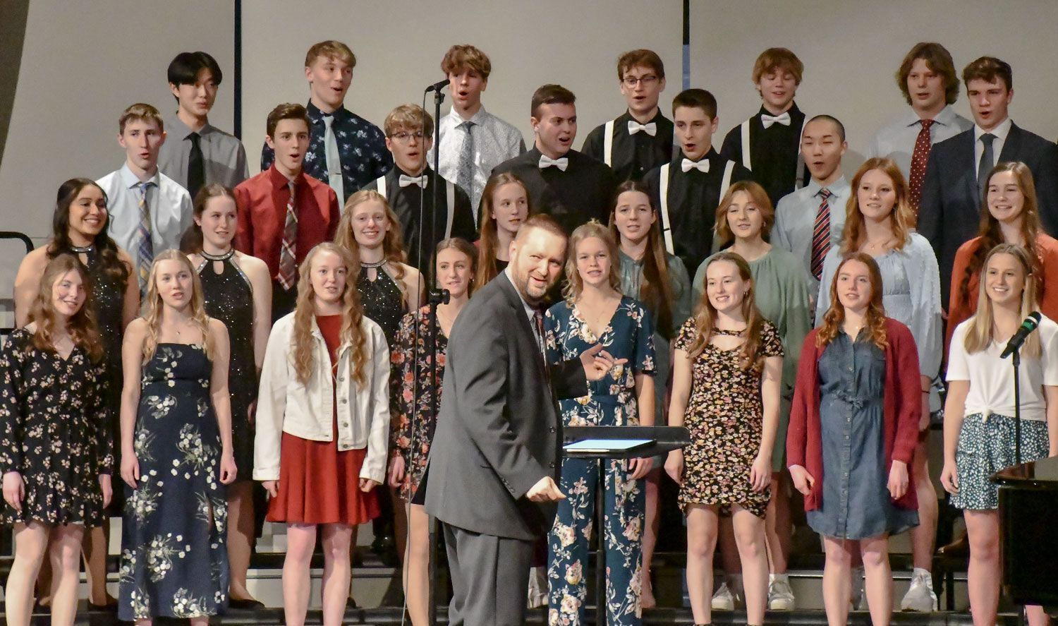 Choir Director, Dan Vogel turned toward the auditorium with student on risers singing