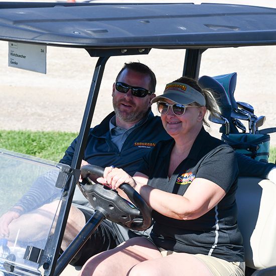 Man and woman in golf cart, heading out to the course