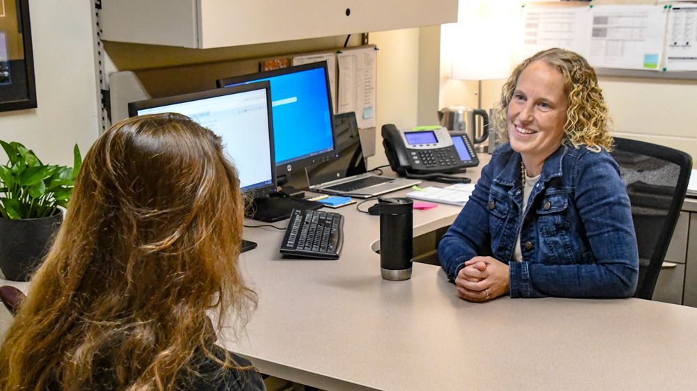 Heidi Wendland at her desk, helping a student