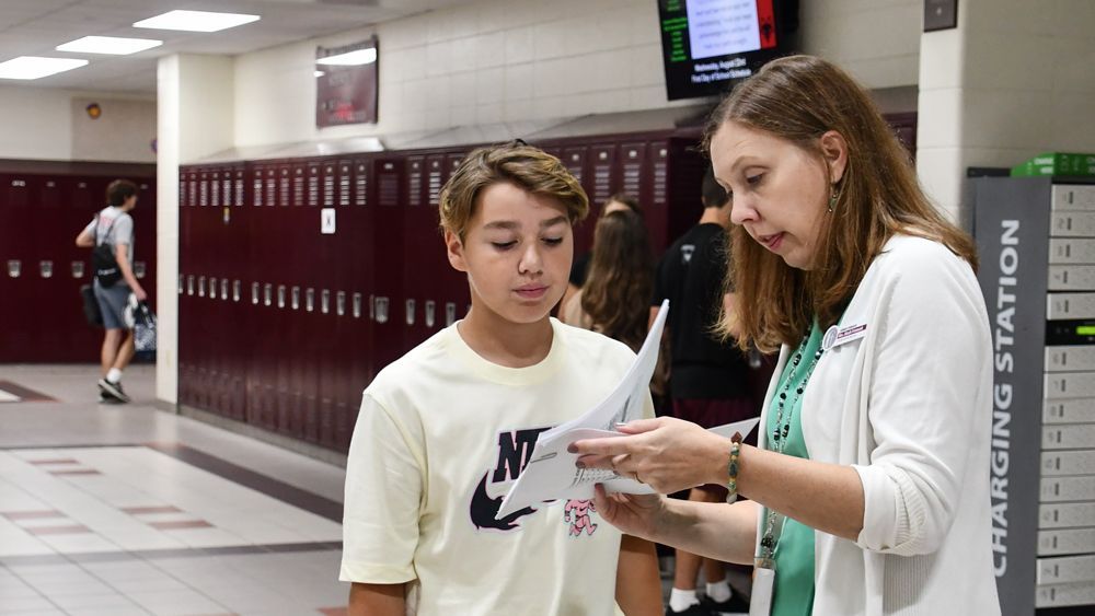 Aleah Friemark working with a student in the hallway at FVL