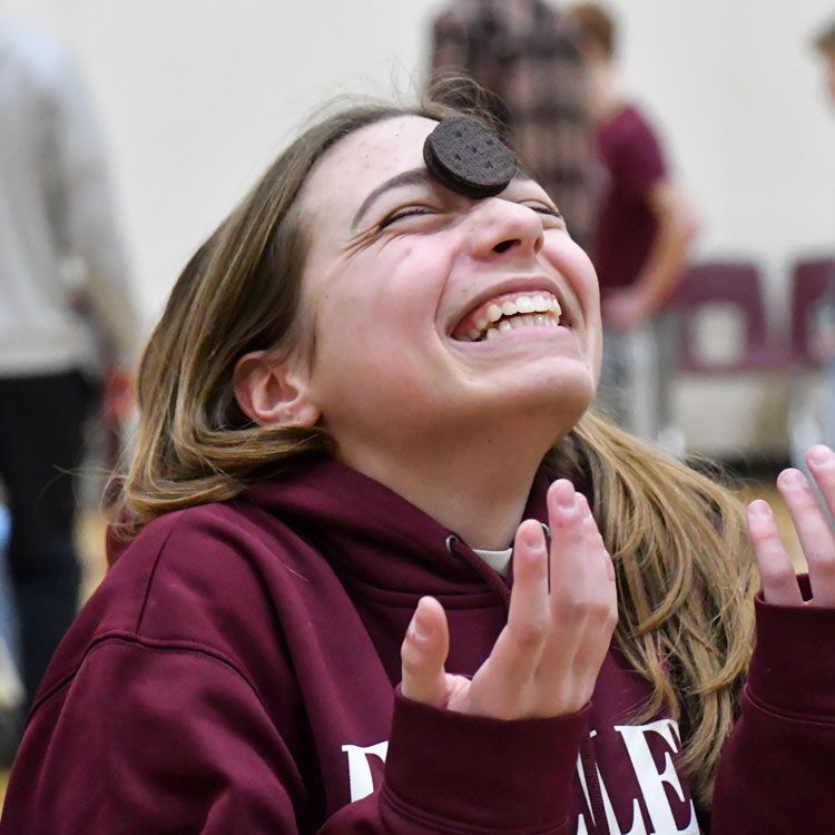 Laughing girl with Oreo Cookie on her forehead between her eyes as she tries to get the cookie into her mouth