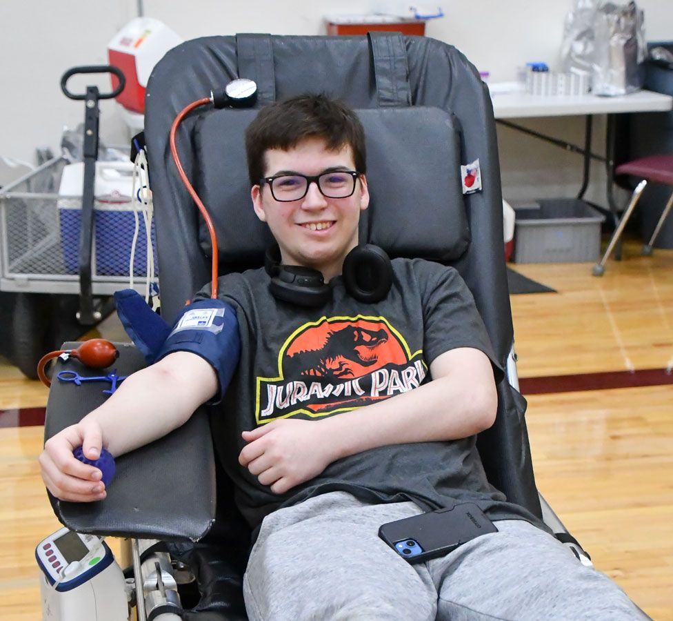 Happy male student donating blood