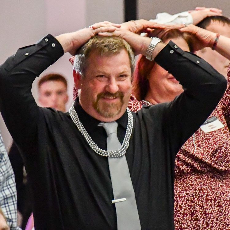 Man with hands on his head and beads around his neck, having fun playing Heads or Tails