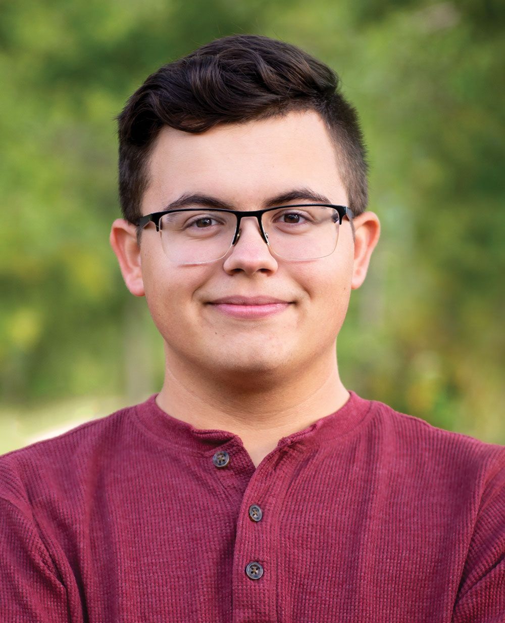 Senior head shot of smiling Benjamin Grady - blurred greenery is in the background
