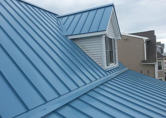 Worker using a yellow roofing nail gun on asphalt shingles