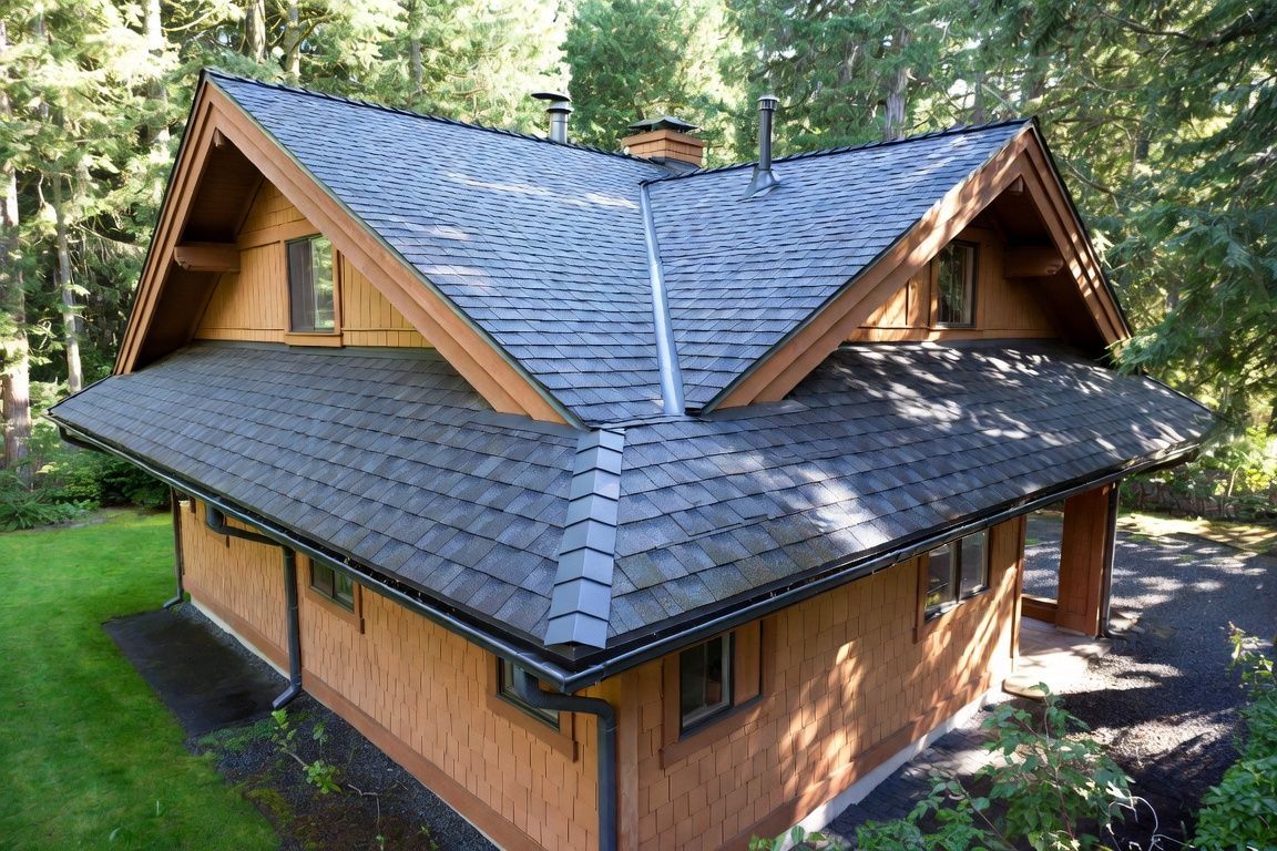 Gloved hand inspecting a roof gutter and perforated leaf guard along dark shingles