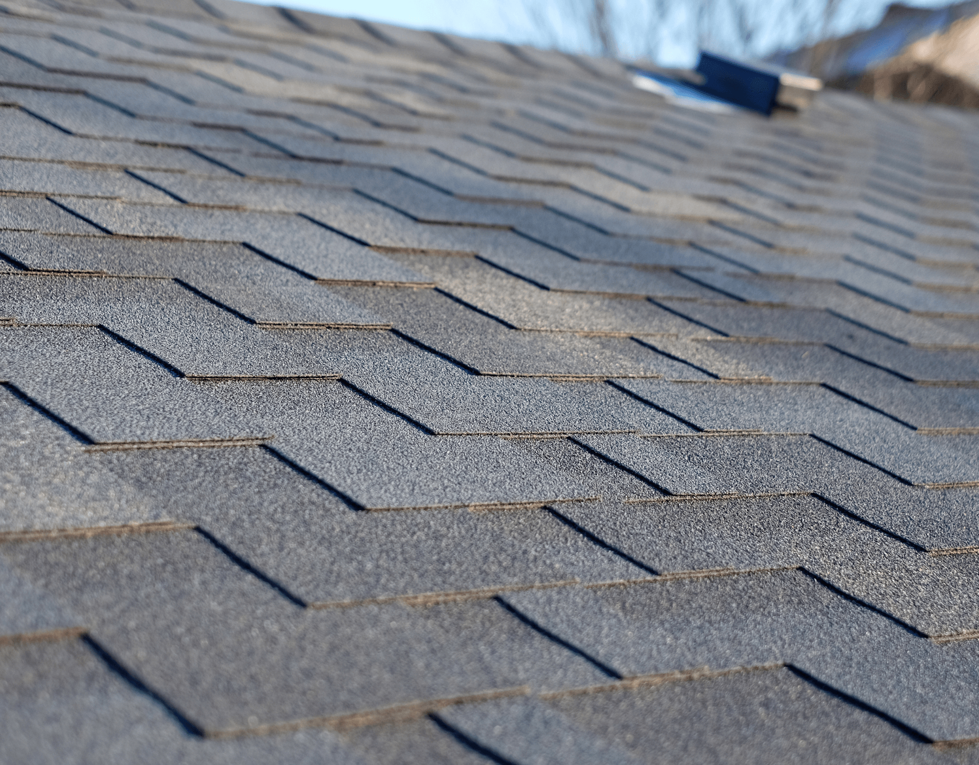 Worker pressure-washing a red tiled roof beside a brick chimney under a blue sky