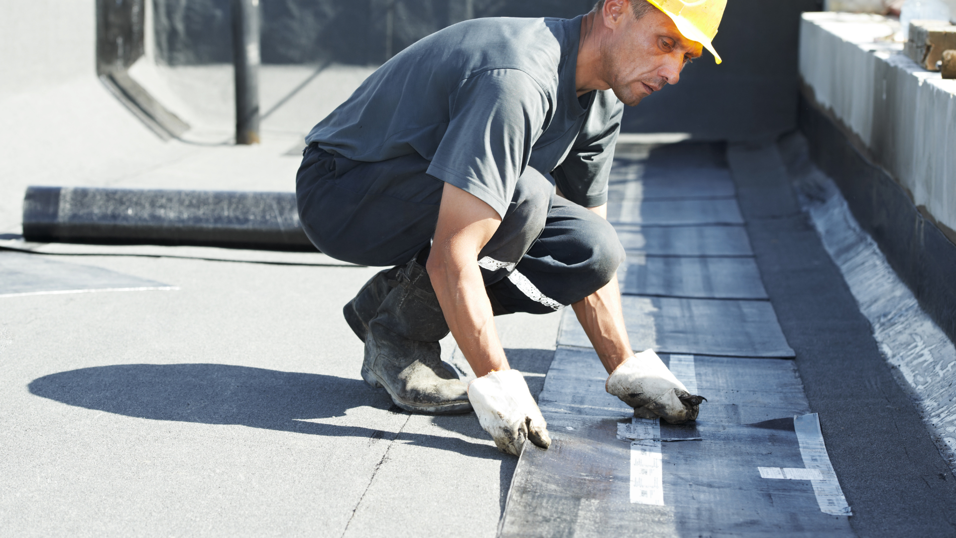 Three roofers installing gray shingles on a house roof under a cloudy sky