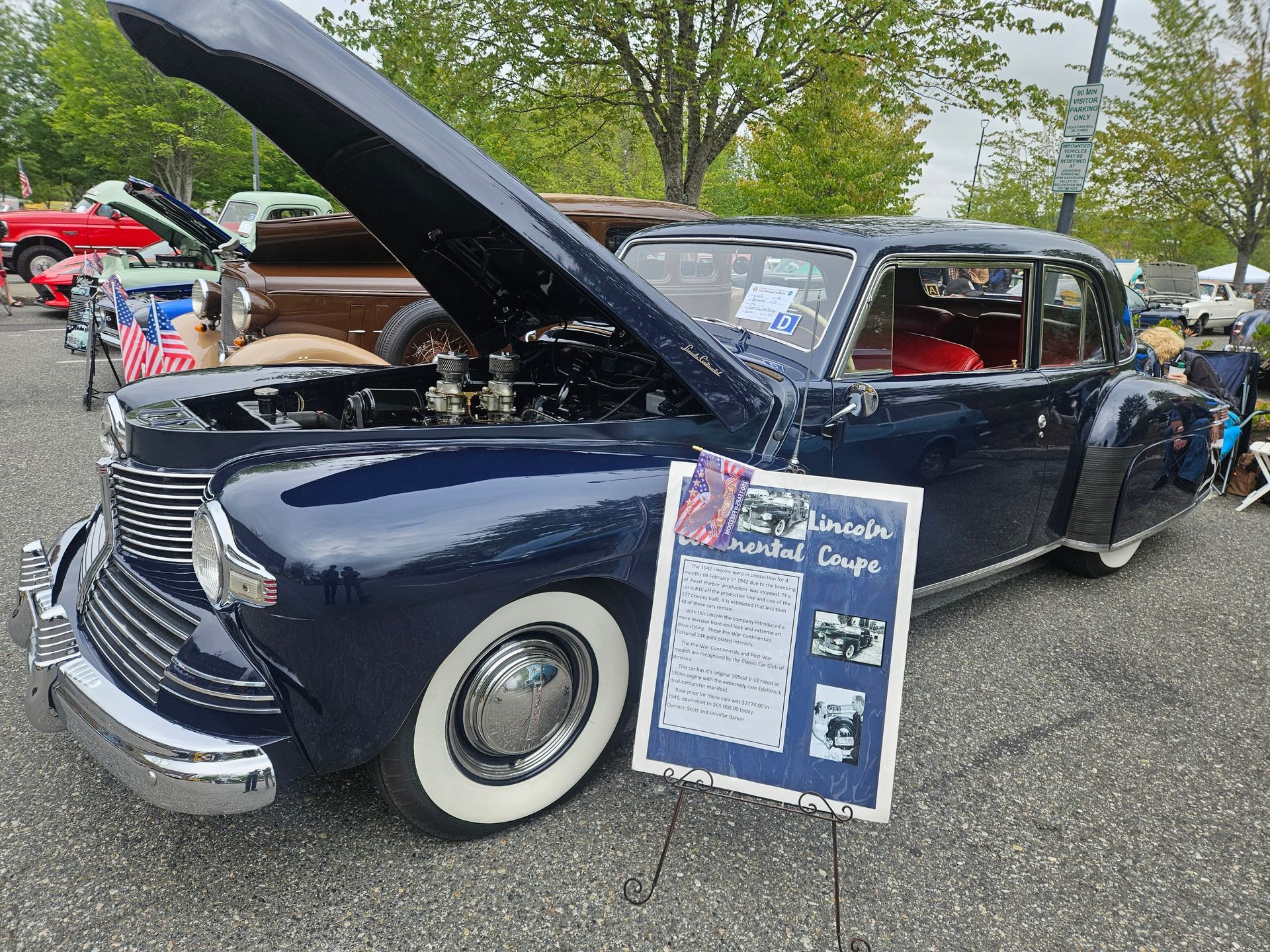 Classic vintage cars lined up on a red carpet display at an outdoor show.