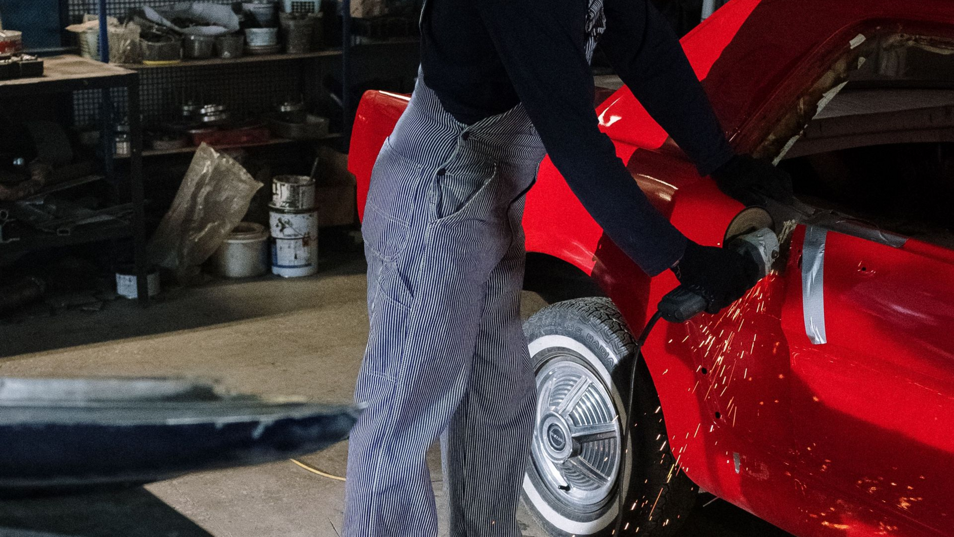 People welding and repairing orange off-road vehicles in a spacious workshop with tools and lifts