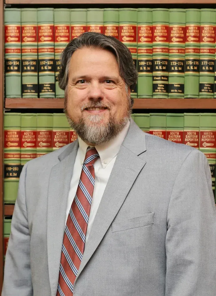 Man in a gray suit and red striped tie standing before shelves of law books