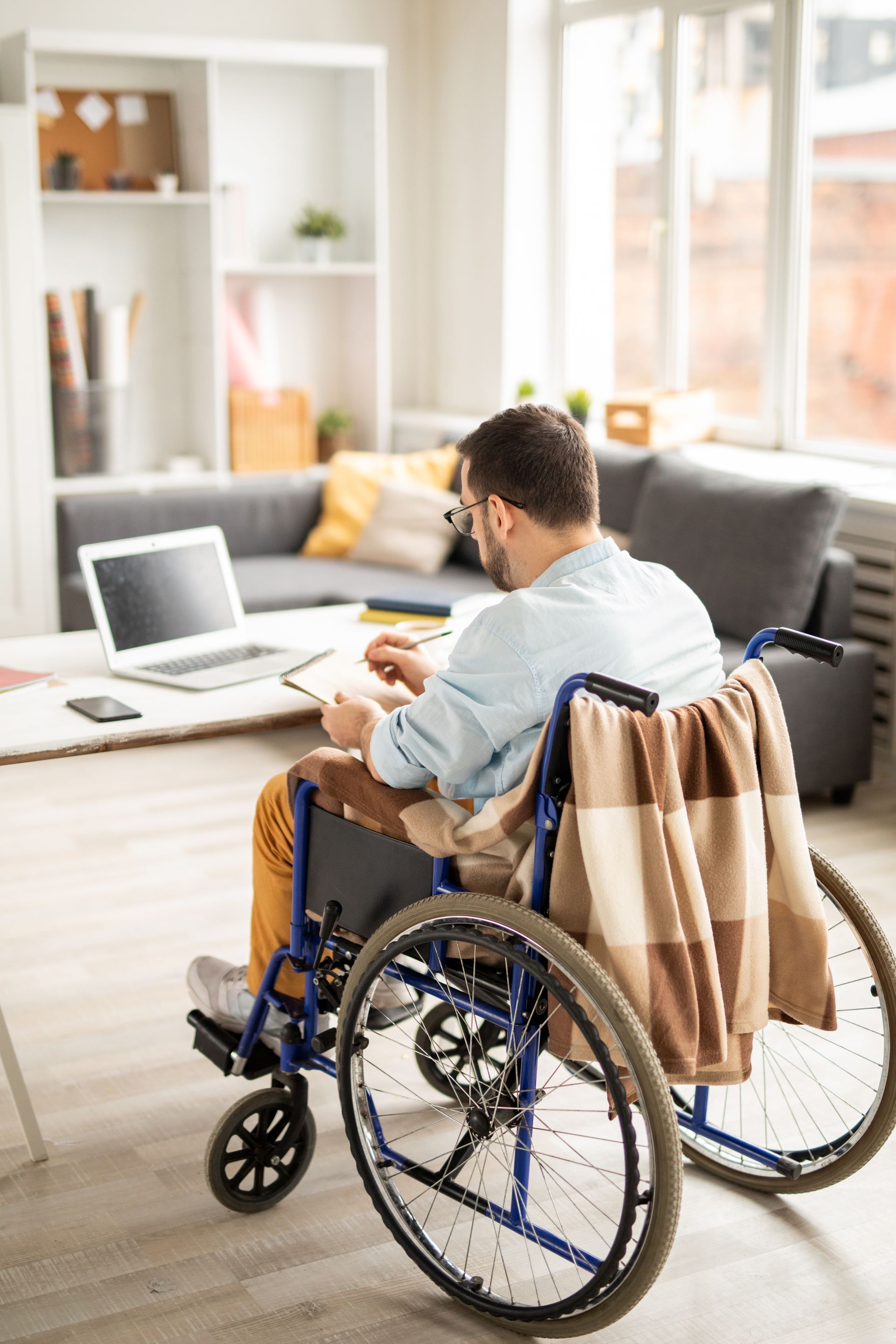 Person in a wheelchair working on a laptop in a bright living room