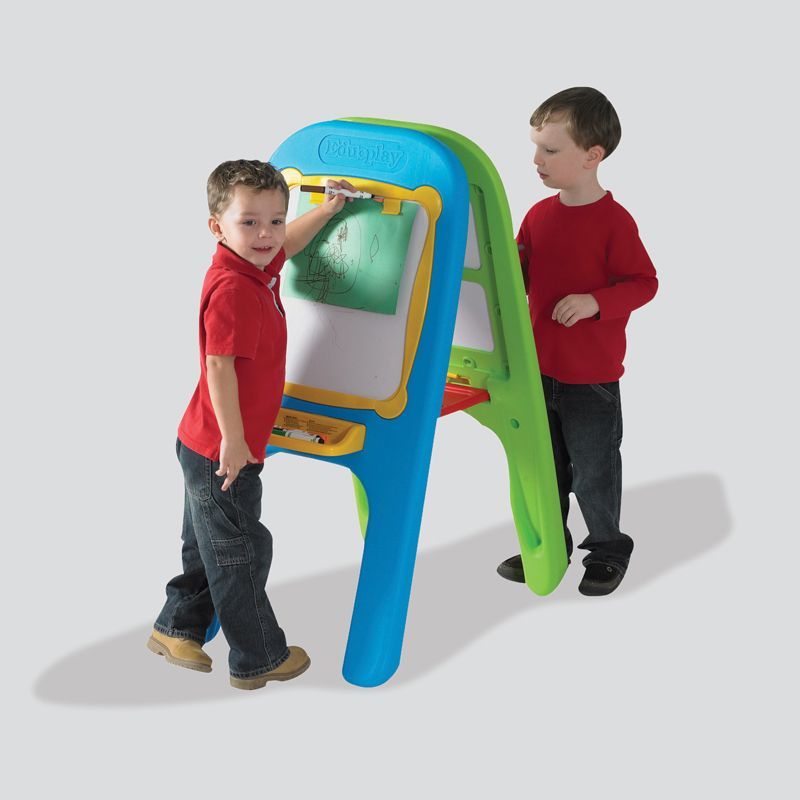 A boy in a red shirt is standing next to a blue and green easel