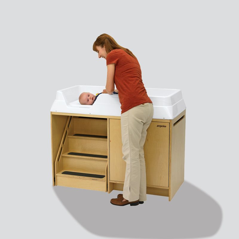 A woman is changing a baby 's diaper on a changing table