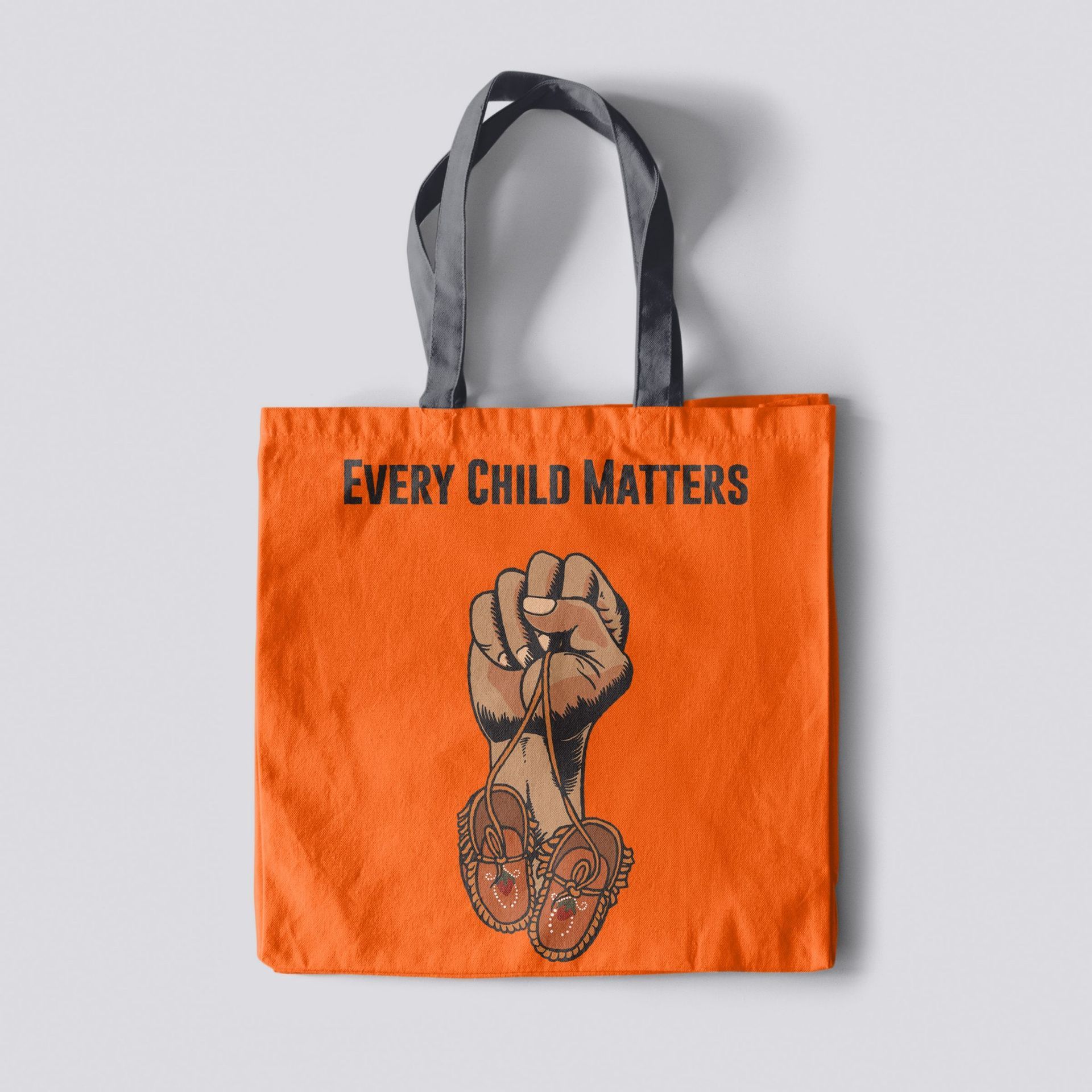 An orange tote bag that says every child matters