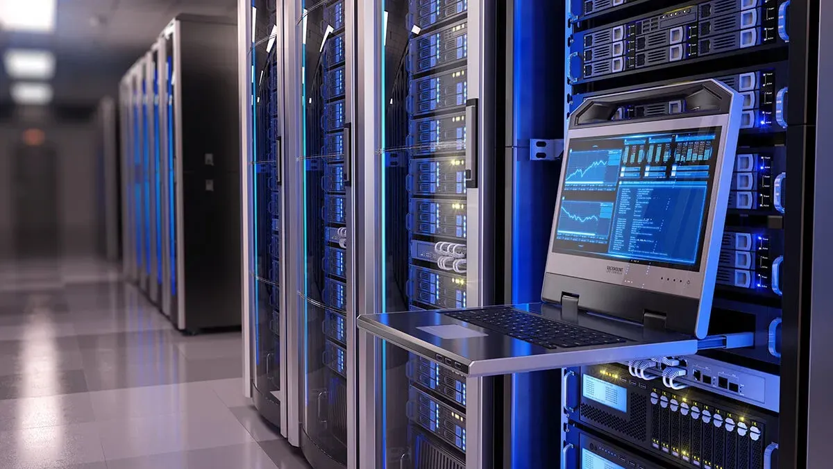A laptop is sitting on a shelf in a server room.