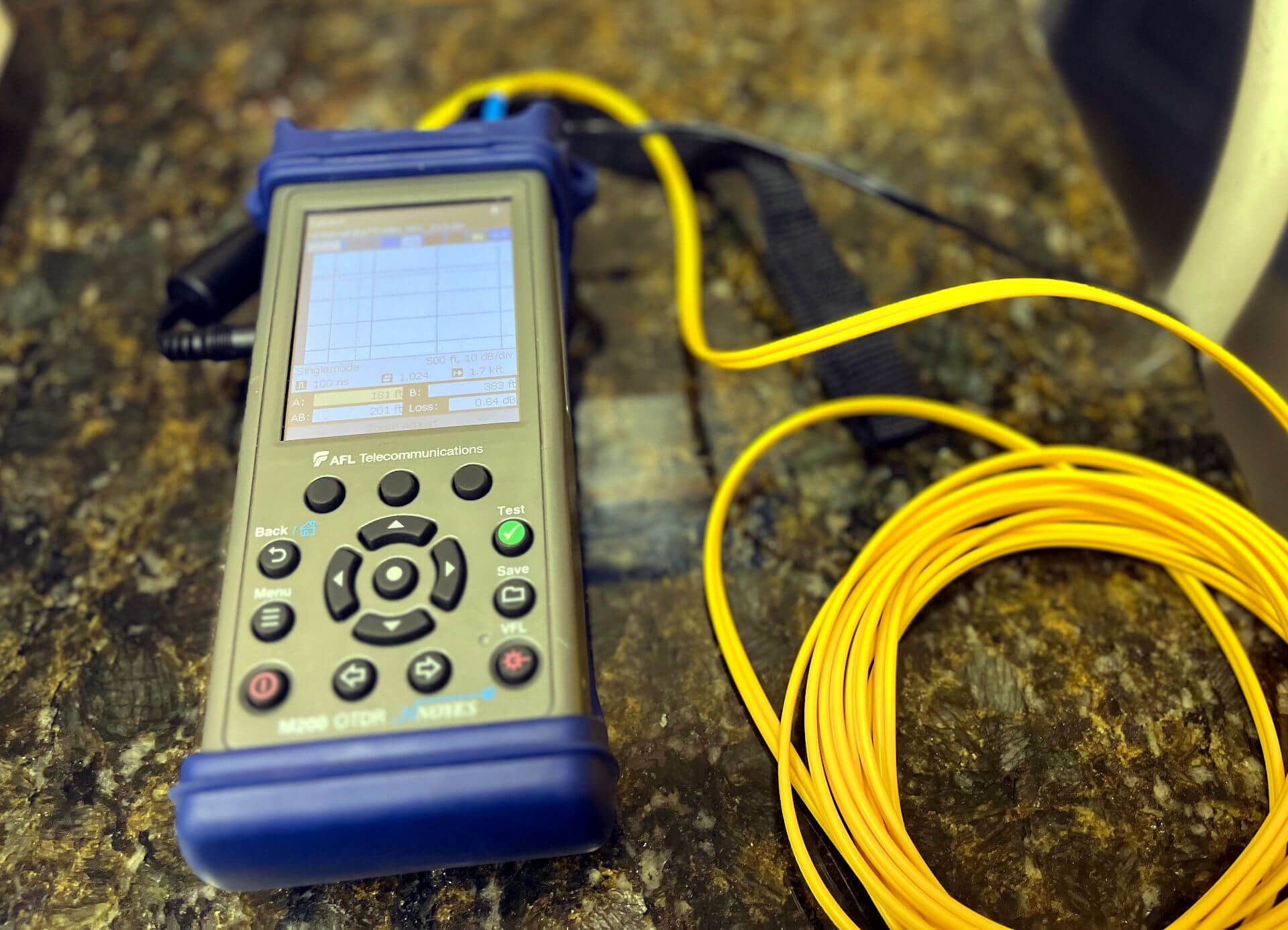 A OTDR device is sitting on a counter next to a fiber cable.