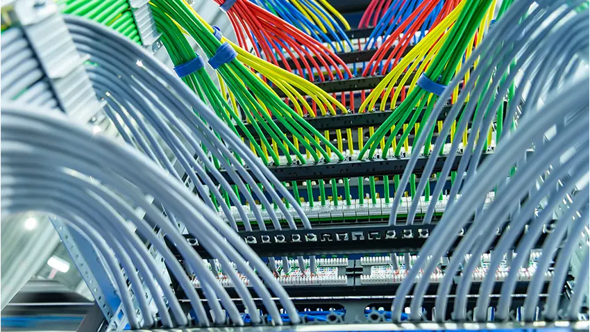 A bunch of wires are connected to a patch panel in a data center.