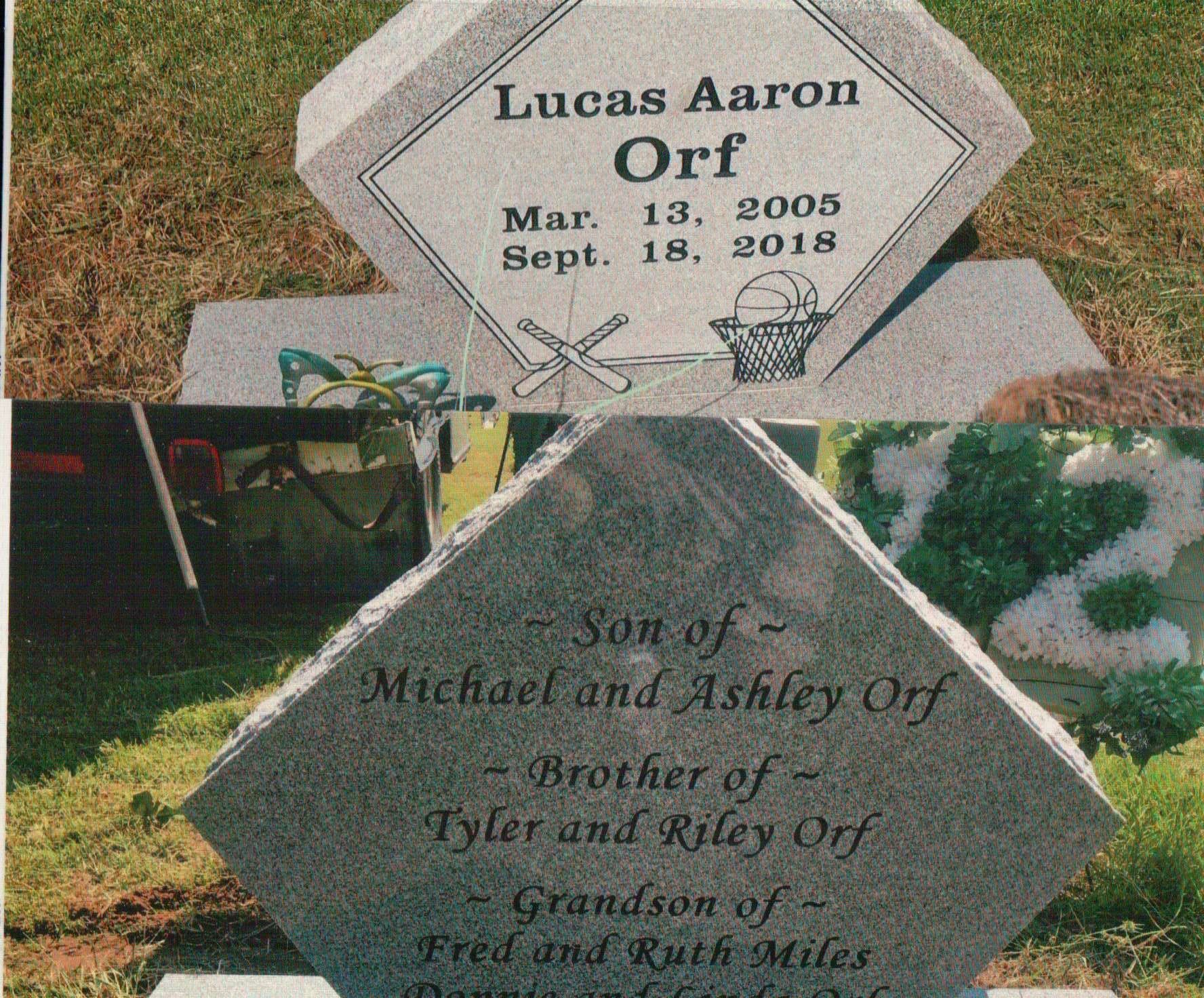 A two-sided granite headstone for Lucas Aaron Orf (2005-2018), engraved with family names and sports motifs.