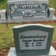 Two gray stone grave markers in a grassy cemetery. The top one reads 
