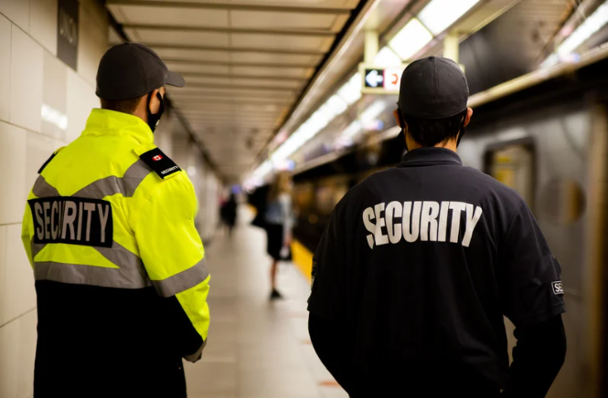 Twee beveiligers staan ​​naast elkaar op een treinstation.