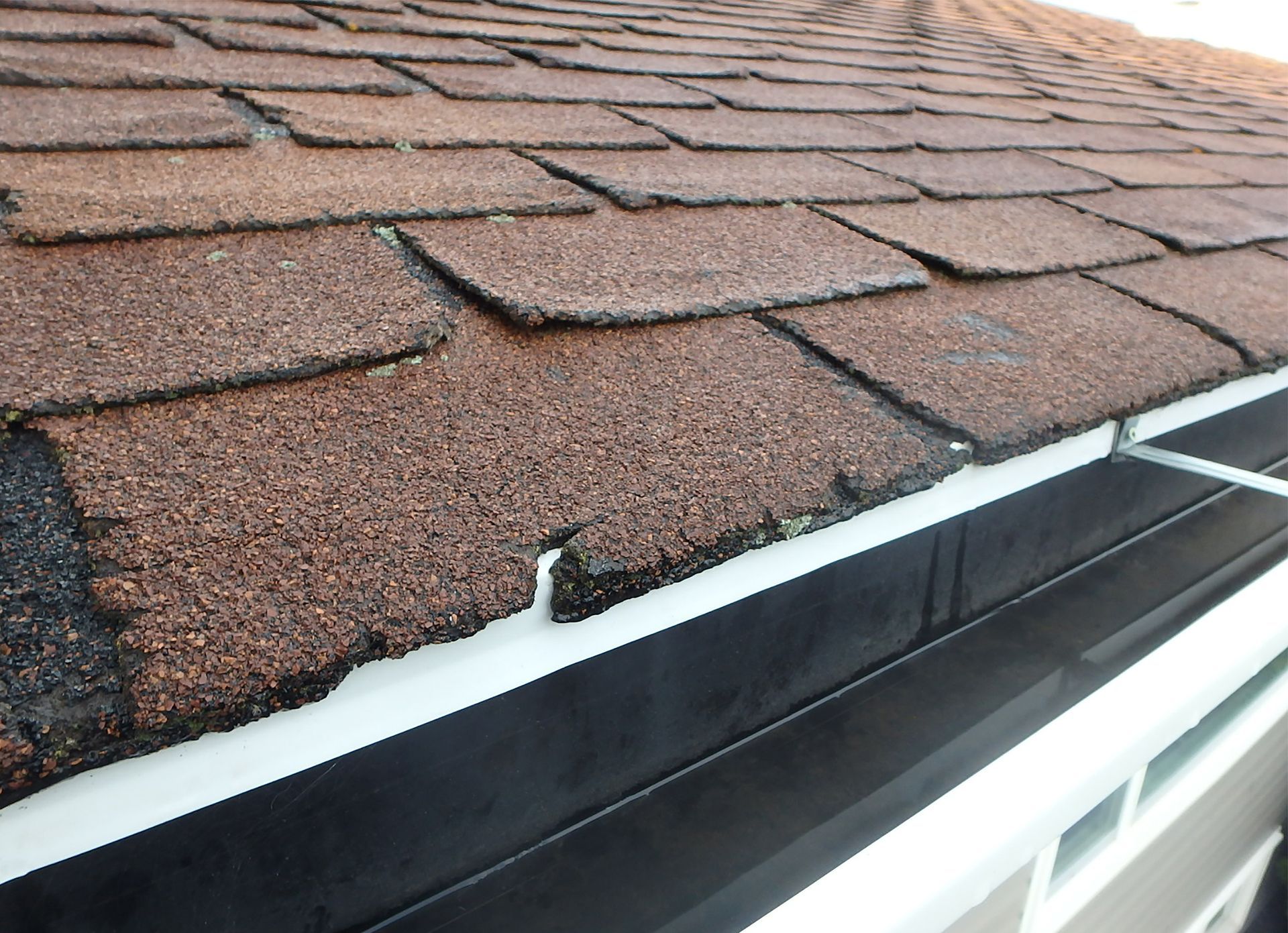 A person is installing shingles on a roof with a hammer.