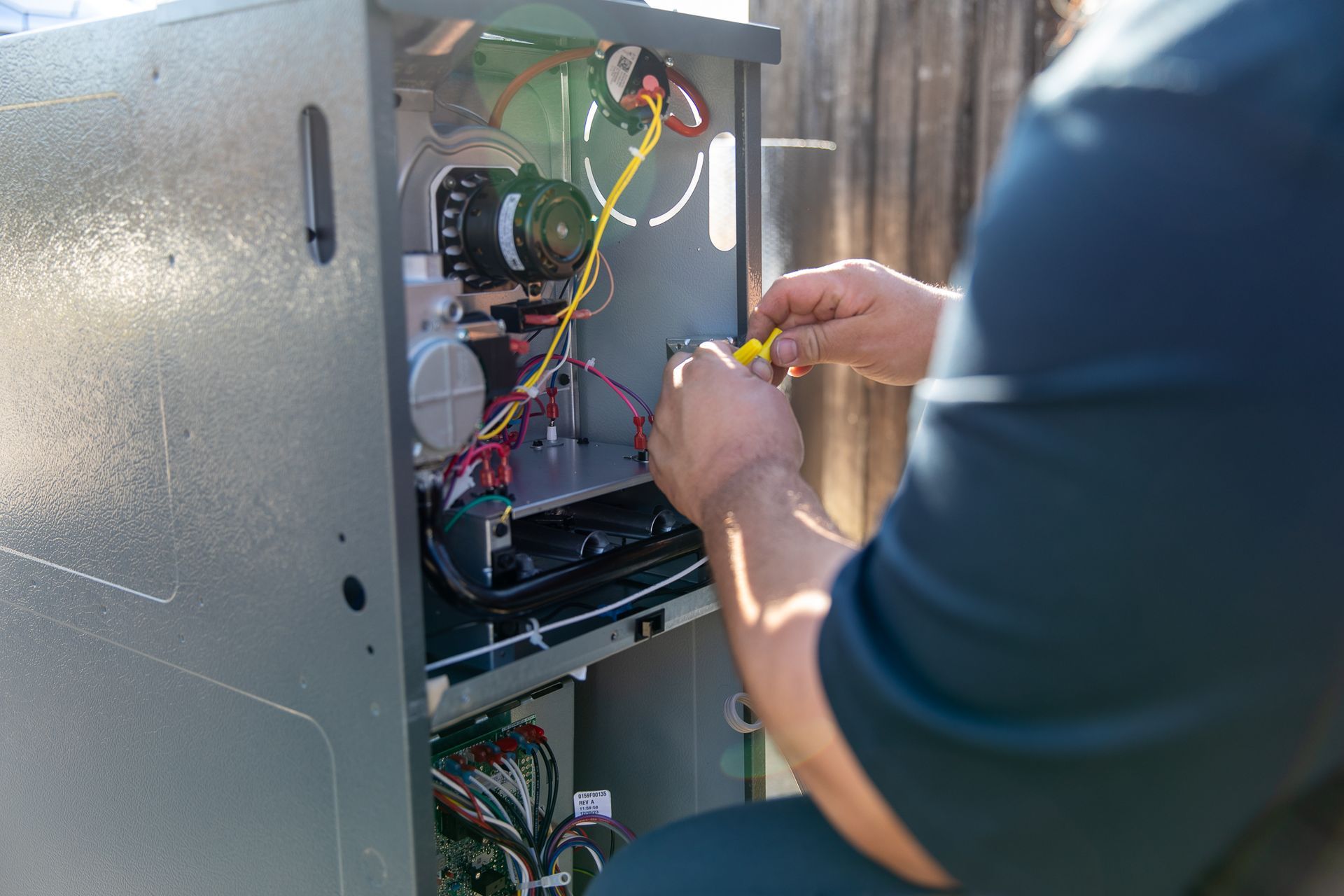 A man is working on an air conditioner with a screwdriver
