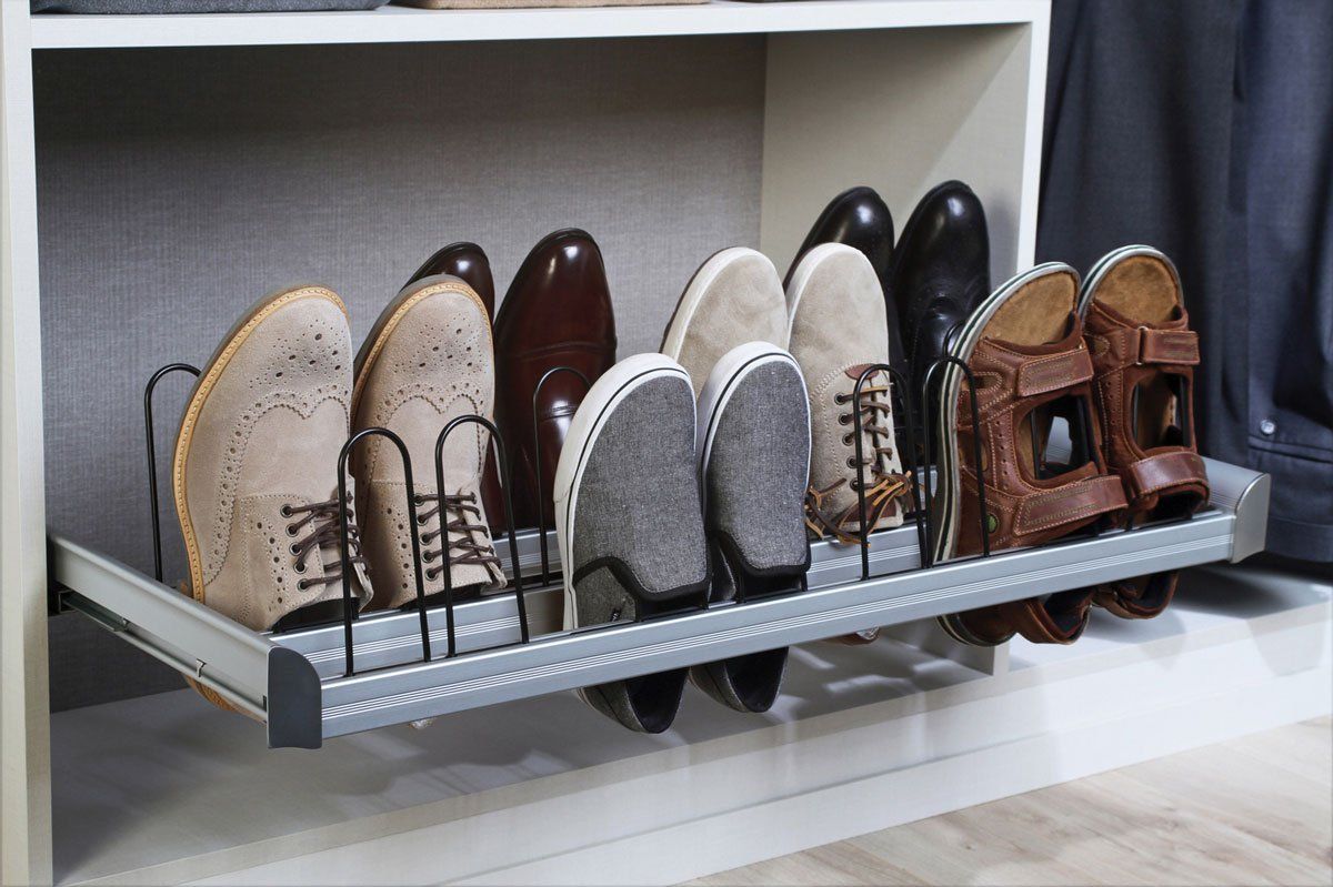A row of shoes sitting on top of a shoe rack in a closet.