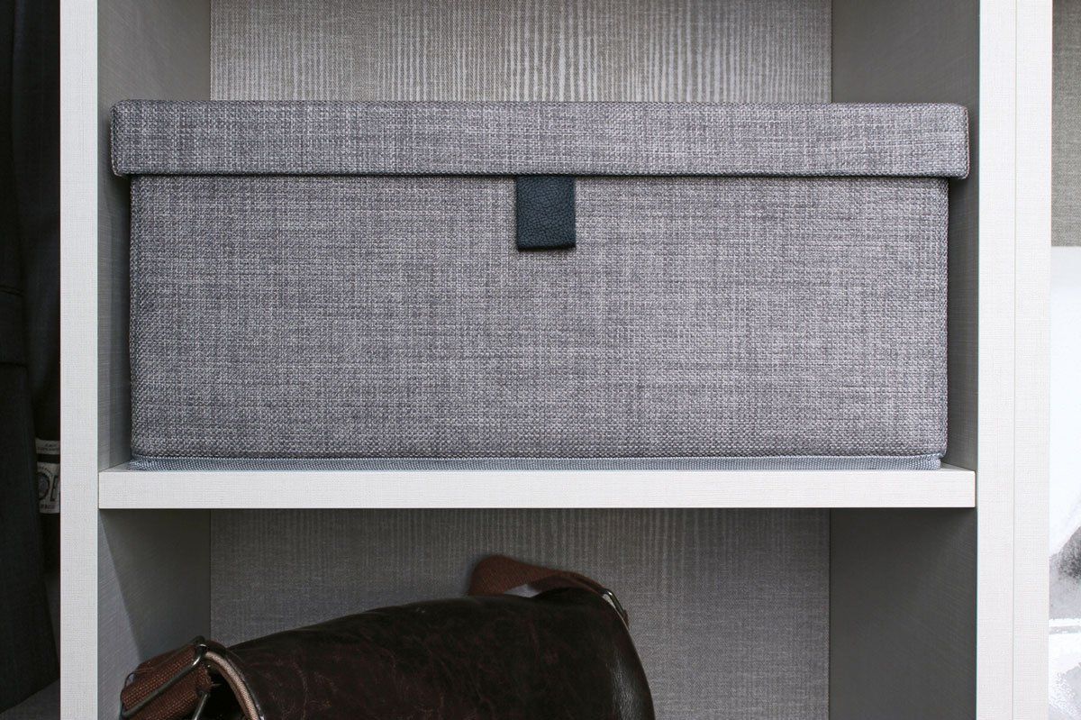 A purse is sitting on a shelf in a closet next to a box.