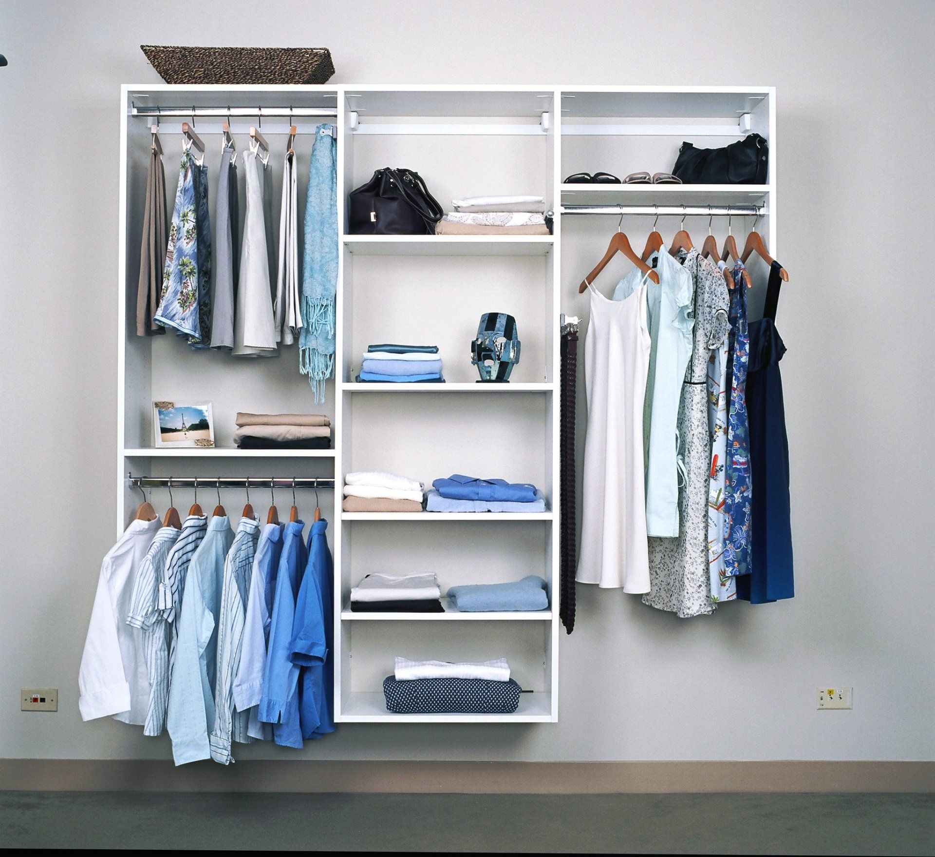 Open white closet with neatly hung and folded clothes in a minimalist room
