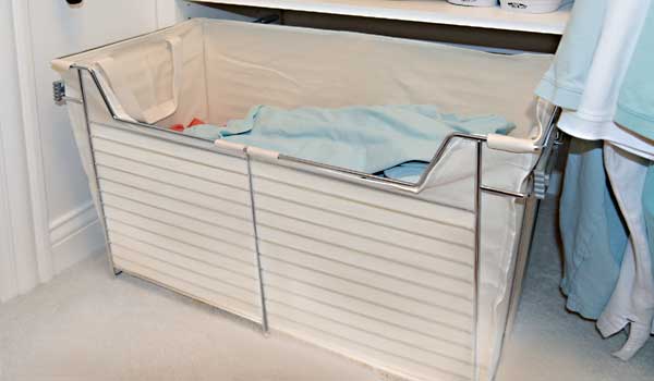 A laundry basket filled with clothes in a closet.