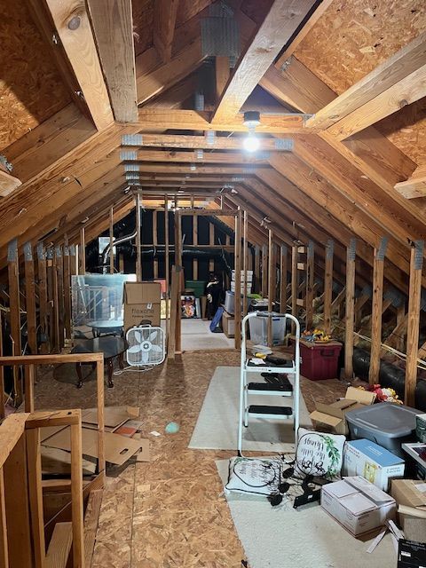 An attic filled with boxes and a ladder.