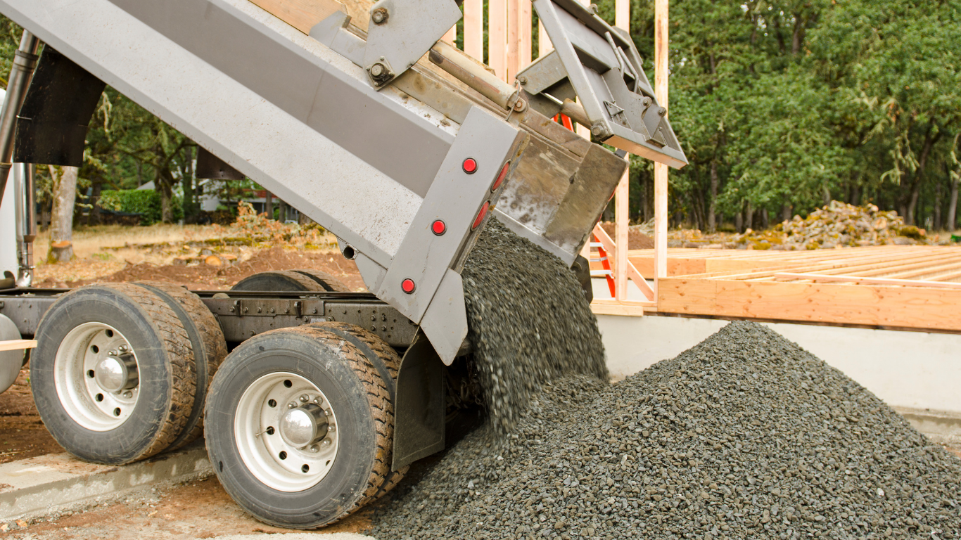 Dump truck unloading gravel at a construction site.
